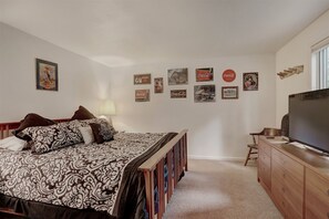 A bedroom with a bed, a TV, a dresser, and wall decorations including vintage Coca-Cola signs. - Timber Hill (Breckenridge)