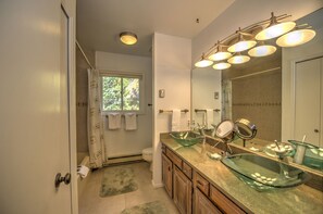 A modern bathroom with a glass sink, a large mirror, and a shower with a glass door. - Timber Hill (Breckenridge)