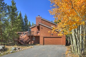A modern log cabin with a wooden exterior, a covered porch, and a staircase leading to an upper level. - Timber Hill (Breckenridge)