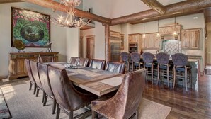 A spacious dining area with a large wooden table and leather chairs, a chandelier, and rustic wooden beams. - Christie Heights Retreat (Breckenridge)