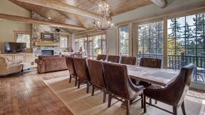 A spacious living room with a large wooden dining table, leather chairs, a fireplace, and a stone accent wall. - Christie Heights Retreat (Breckenridge)