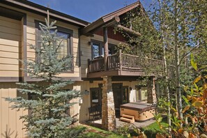 A two-story building with a balcony, stone pillars, and a hot tub.