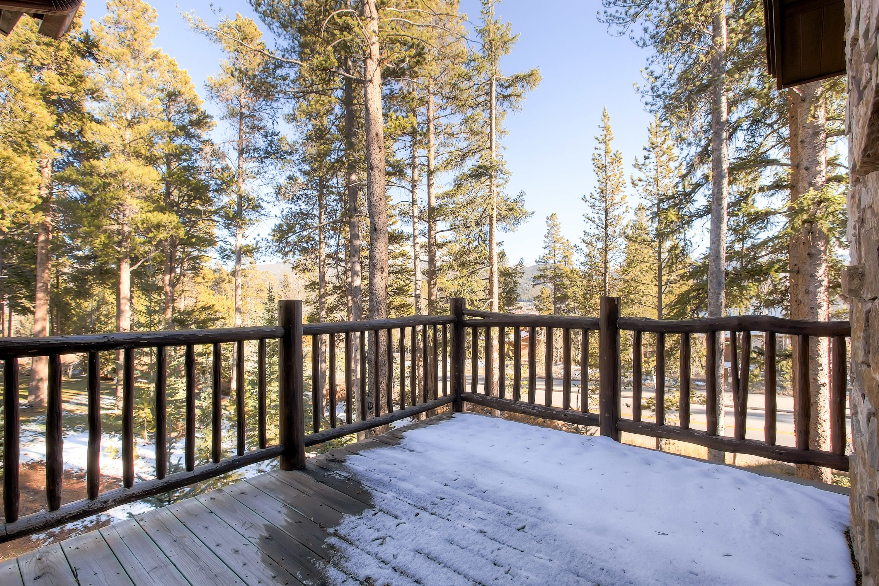 A wooden deck with a railing overlooking a forested area.