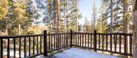 A wooden deck with a railing overlooking a forested area.