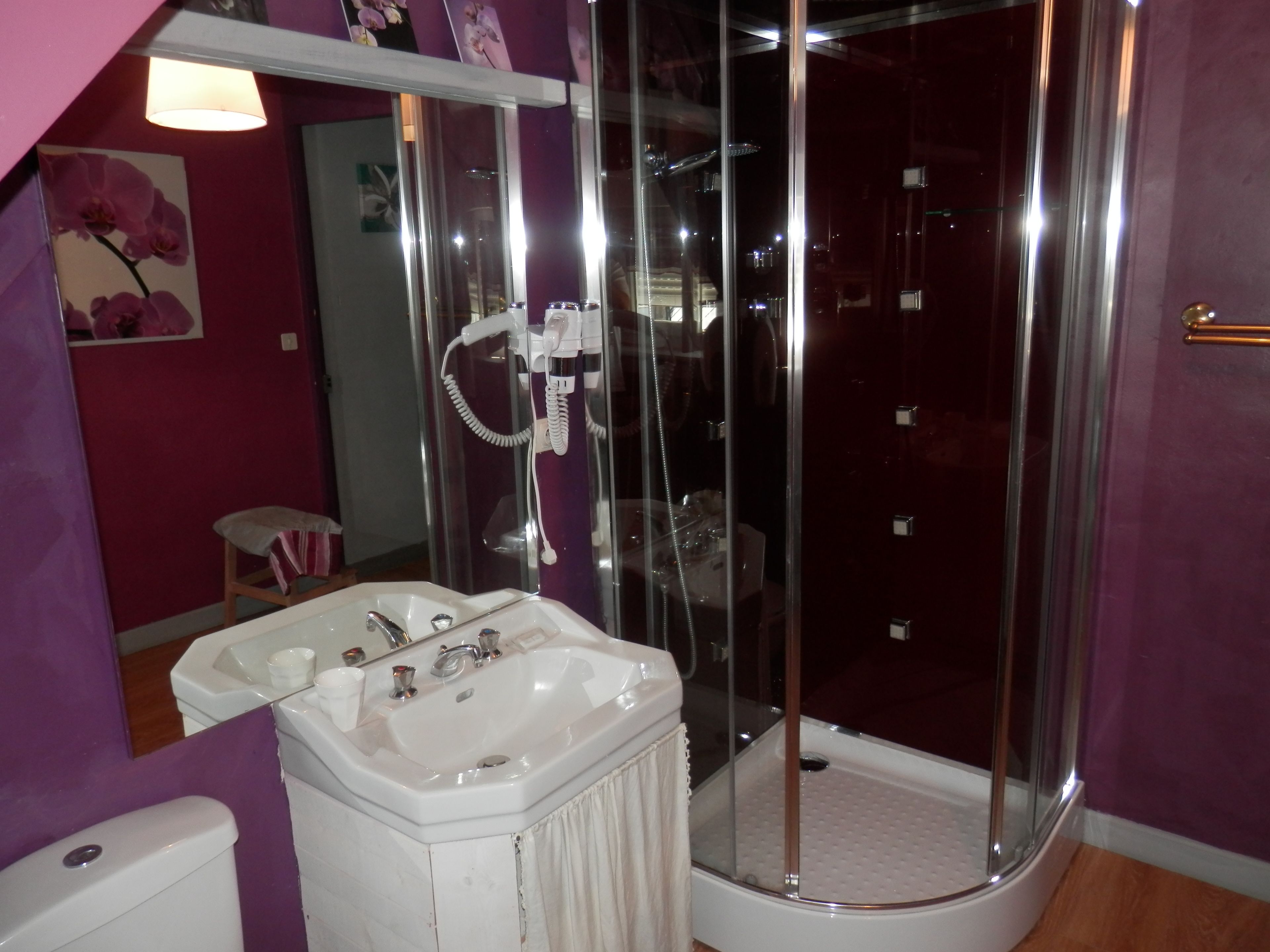 A bathroom with a glass-enclosed shower, a white sink, and a toilet.