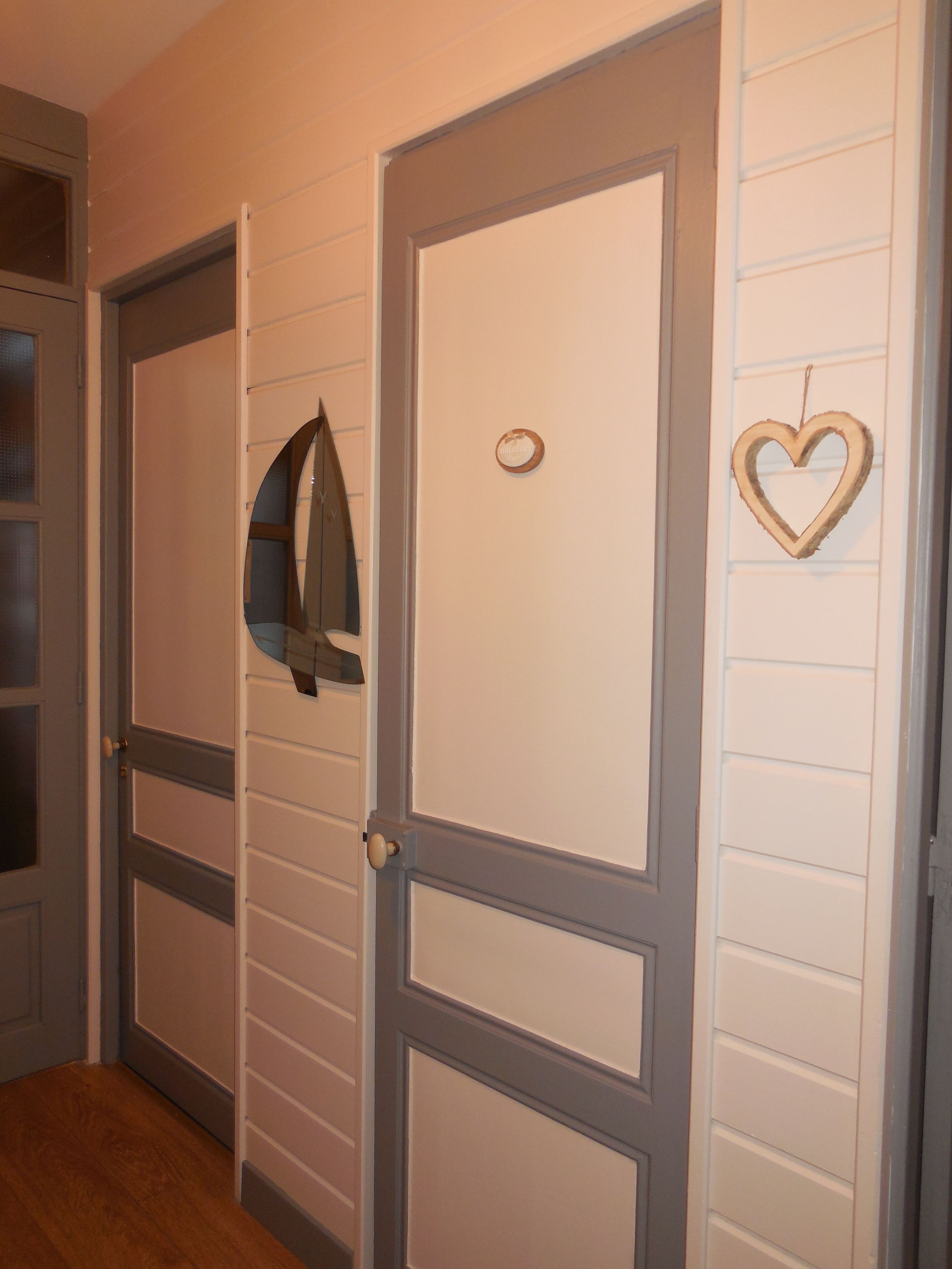 Un pasillo con puertas cerradas, un abrigo colgado de una puerta y una decoración con forma de corazón en la pared.