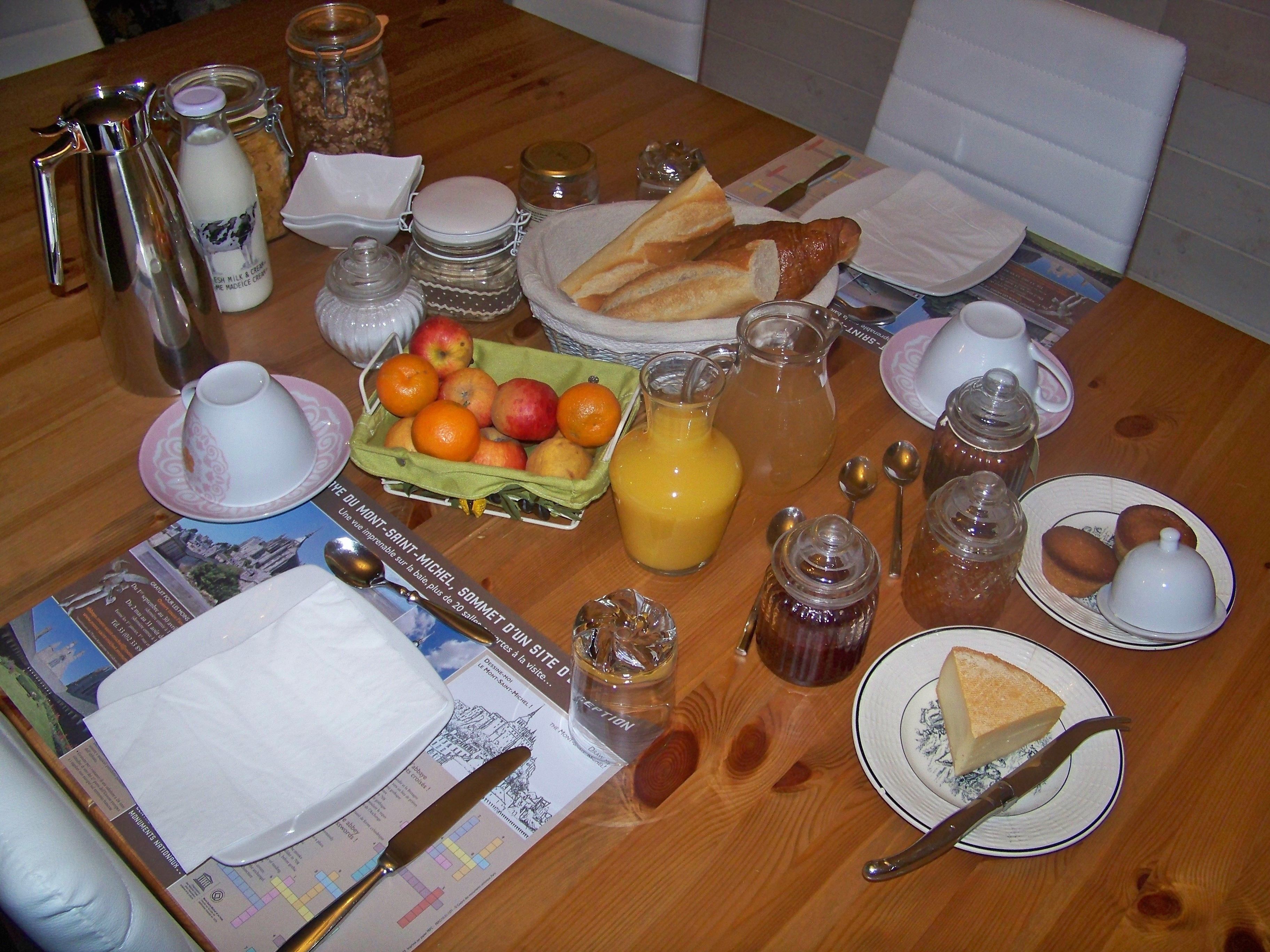 A breakfast table with bread, fruit, and beverages.