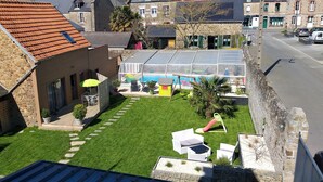 A residential property with a swimming pool, solar panels, a patio with outdoor furniture, and a stone wall. - L'Âme Du Gourmand (Pontorson)