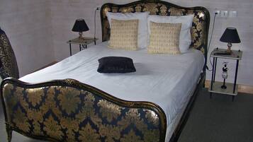 Un letto con una testiera e un bordo inferiore scuri e decorati, due comodini con lampade e cuscini a fantasia.