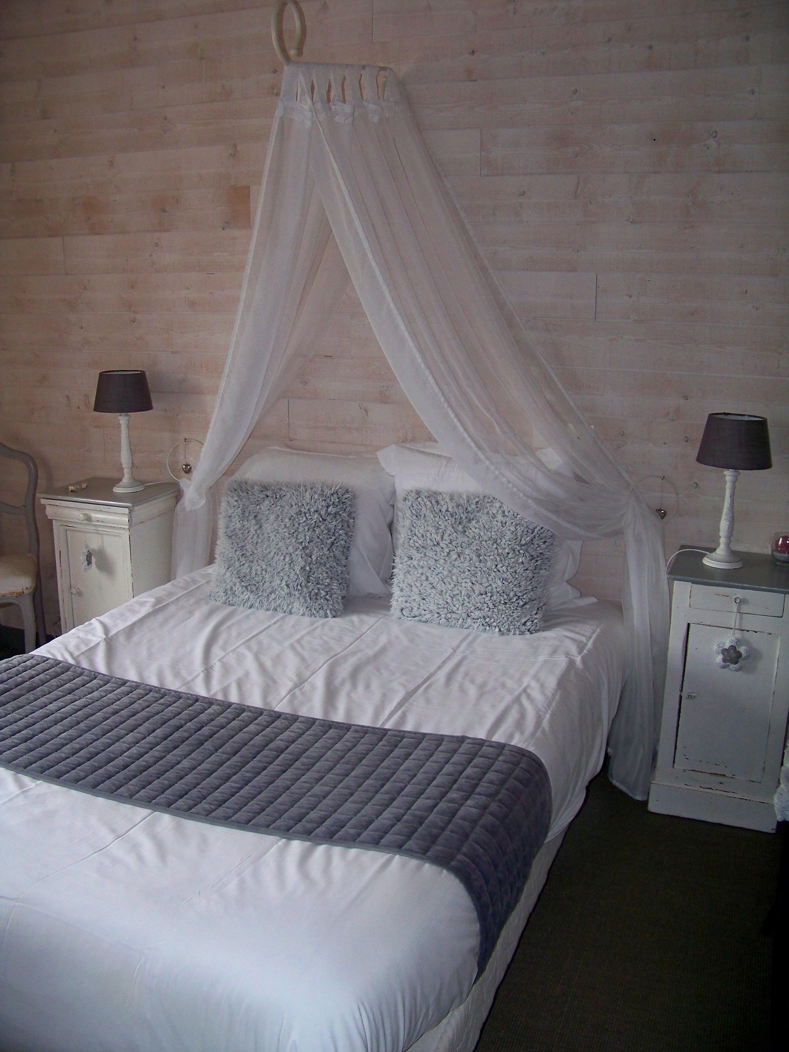 Une chambre à coucher avec un lit, deux tables de chevet, une chaise et un lit à baldaquin.