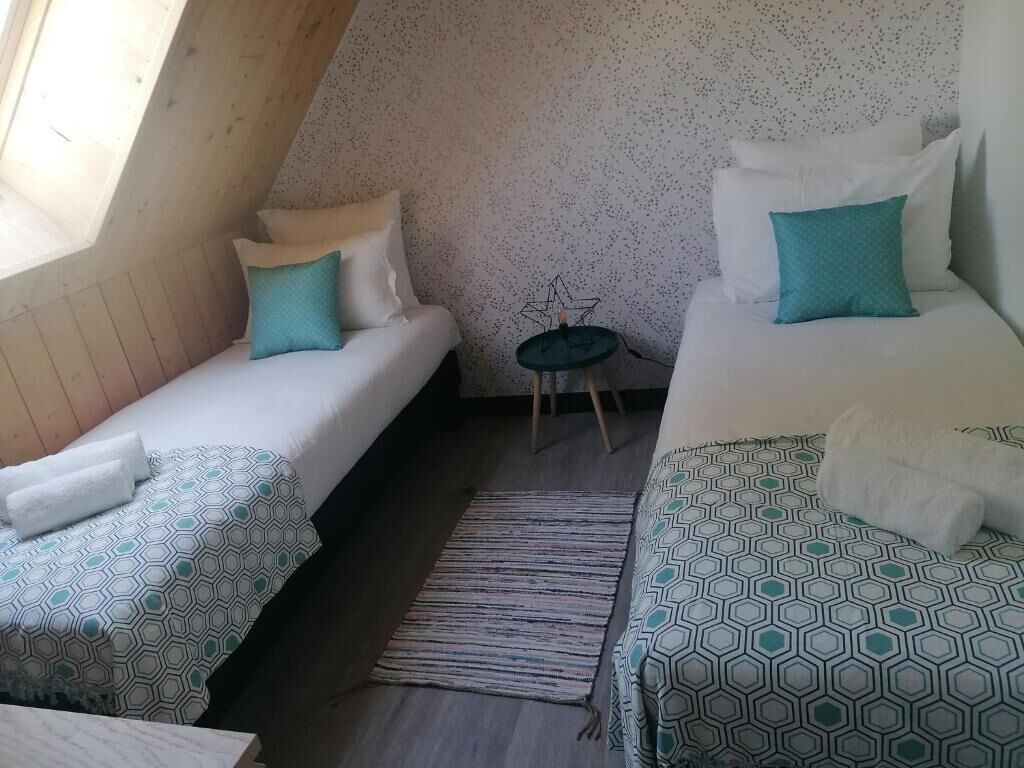 A small, cozy room with two beds, a small table, and a sloped ceiling.