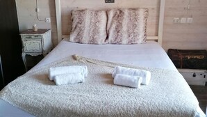 A bed with a white canopy, a fluffy pillow, and two rolled towels. - L'Âme Du Gourmand (Pontorson)