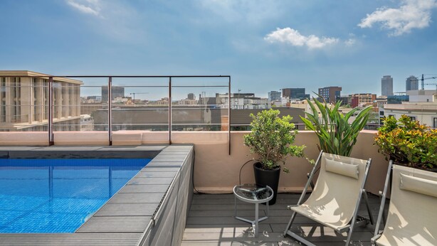 A rooftop pool with a city view, lounge chairs, and potted plants. - Aspasios Poblenou Apartments (Barcelona)