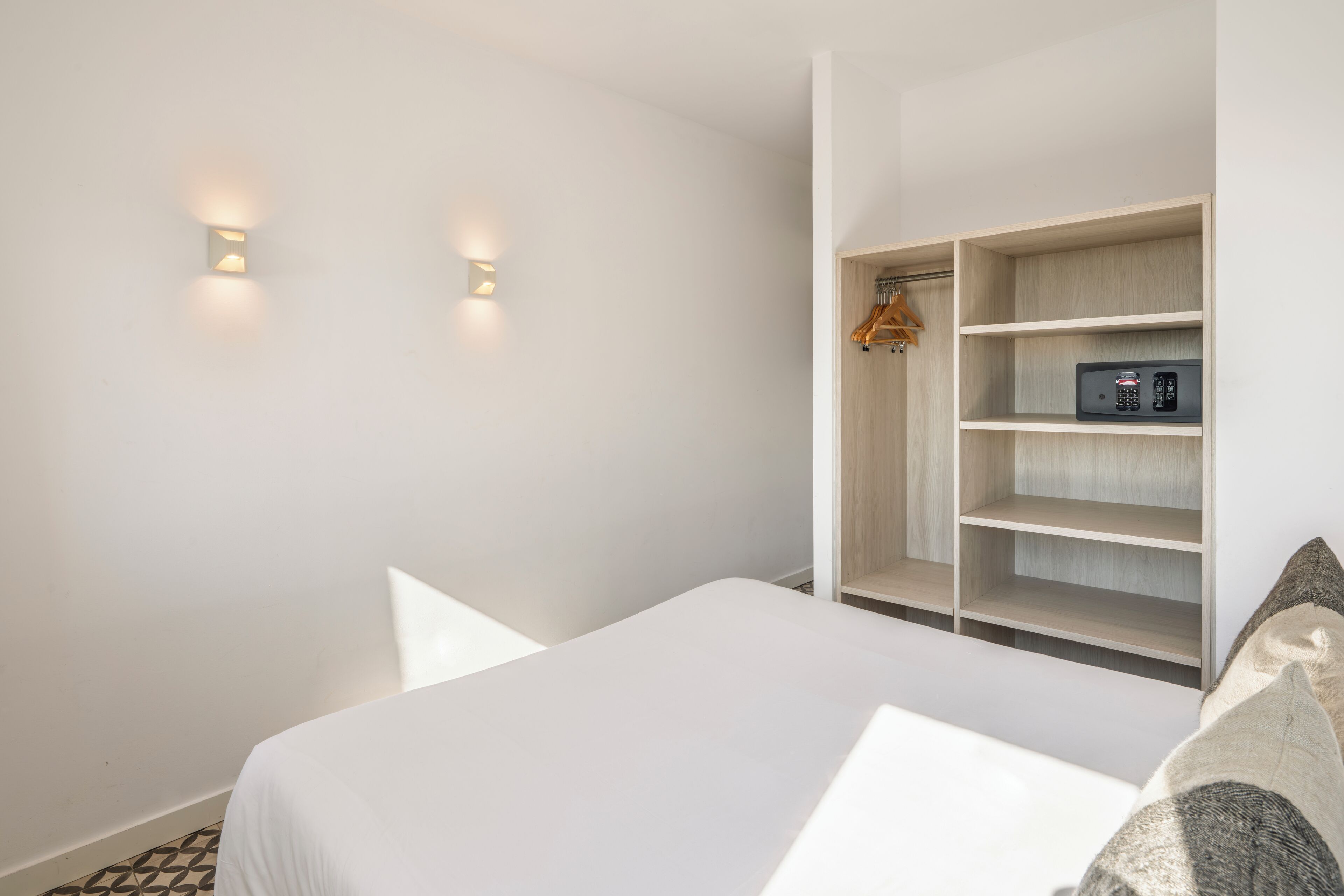 Een slaapkamer met een bed, een kledingkast en twee lampen aan de muur.