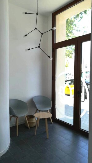 A corner of a room with two grey chairs, a small wooden table, and a hanging light fixture. - Aspasios Poblenou Apartments  (Barcelona)