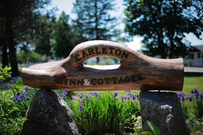 A wooden sign with the text "Carleton Inn & Cottages" mounted on two rocks.