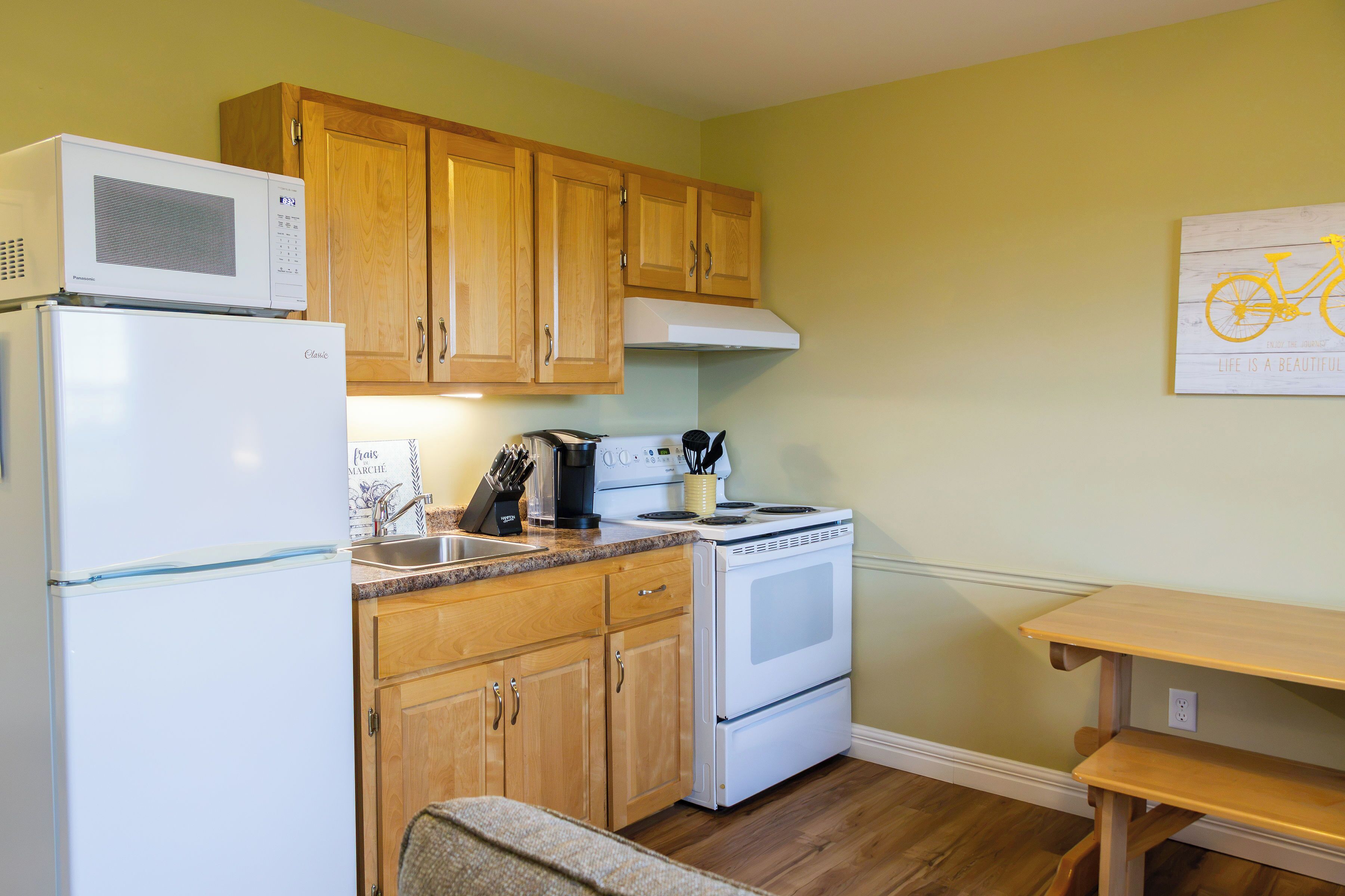 A kitchen with wooden cabinets, a white refrigerator, a stove, and a coffee maker.