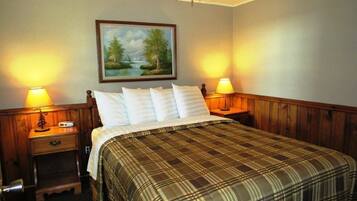 Una habitación de hotel con una cama, dos mesitas de noche, una lámpara y un cuadro en la pared.