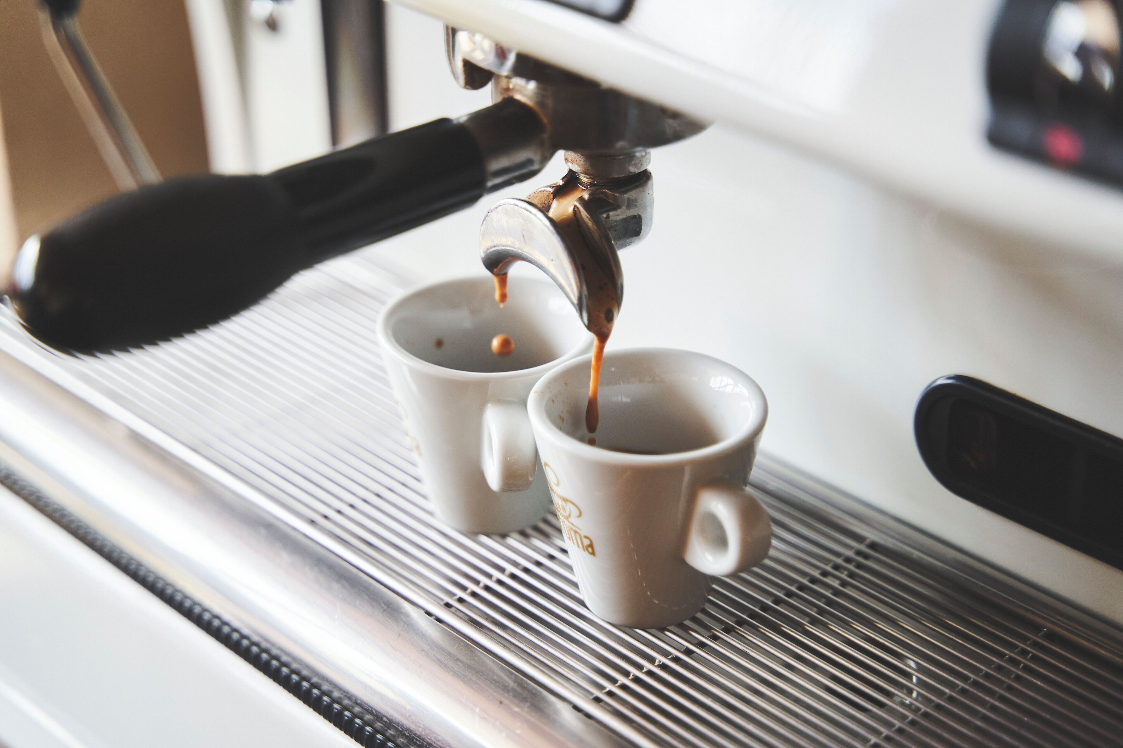 Eine Kaffeemaschine gibt Espresso in zwei Tassen ab.