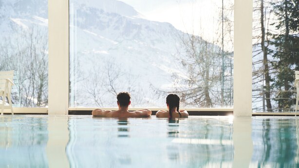 A couple relaxing in a pool with a mountain view. - Hotel Mondolè (Frabosa Sottana)