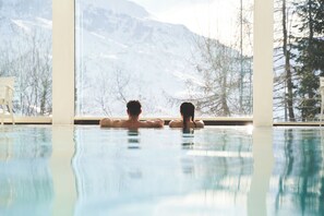 Ett par som kopplar av i en pool med utsikt över ett berg.