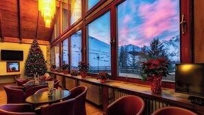 A restaurant with a view of a snowy mountain and a Christmas tree. - Hotel Mondolè (Frabosa Sottana)