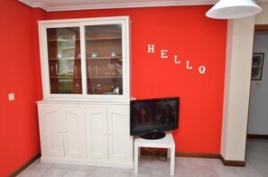 Cozy room with a vibrant wall, a cabinet with glass doors, and a TV on a small stand.