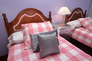 Cozy retreat with a single bed, bedside table, and lamp, set against a vibrant purple wall.