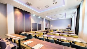 Un salón de conferencias con varias mesas y sillas, equipado con tarjetas de identificación y bolígrafos.