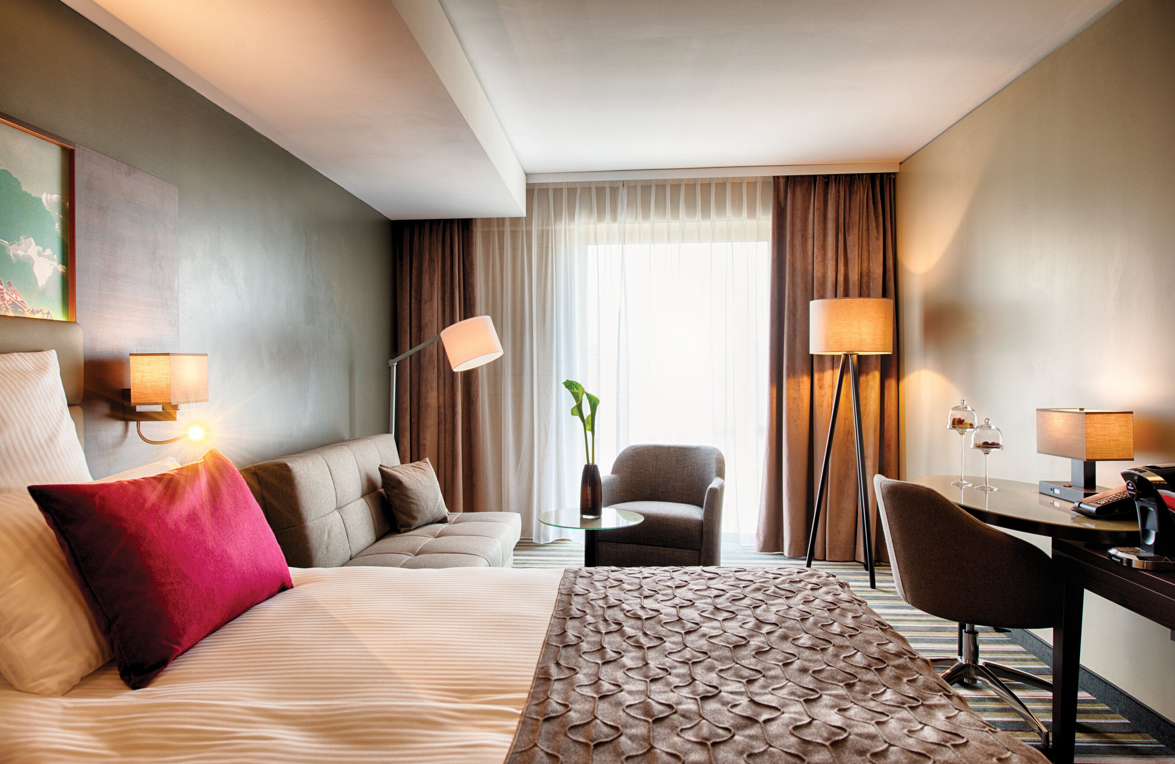 Una habitación de hotel con cama, escritorio, silla y una mesita.