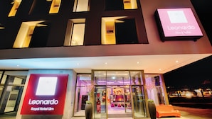 Exterior del Hotel Leonardo Royal Ulm, con entrada de vidrio y un cartel.