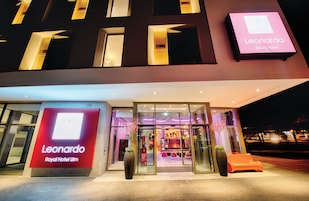 Exterior del Hotel Leonardo Royal Ulm, con entrada de vidrio y un cartel.