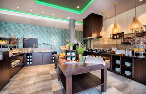 A modern kitchen with a central island, built-in cabinets, and a variety of food items and utensils. - Leonardo Royal Hotel Ulm (Ulm)