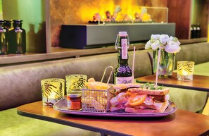 Una mesa con un sándwich, una botella de vino y vasos decorativos.