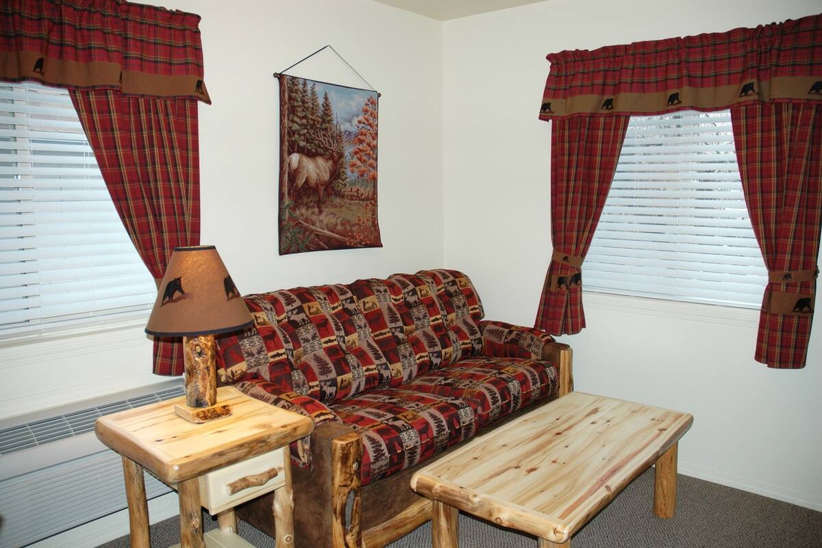 Una habitación acogedora con un sofá de cuadros, una mesa de centro de madera y una lámpara sobre una mesita auxiliar.