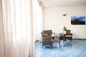 Quarto com uma mesa de jantar e cadeiras, um vaso de planta e um quadro na parede.