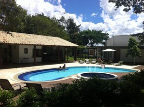A swimming pool with lounge chairs and a covered seating area. - Pousada Boutique Oratorio (Tiradentes)