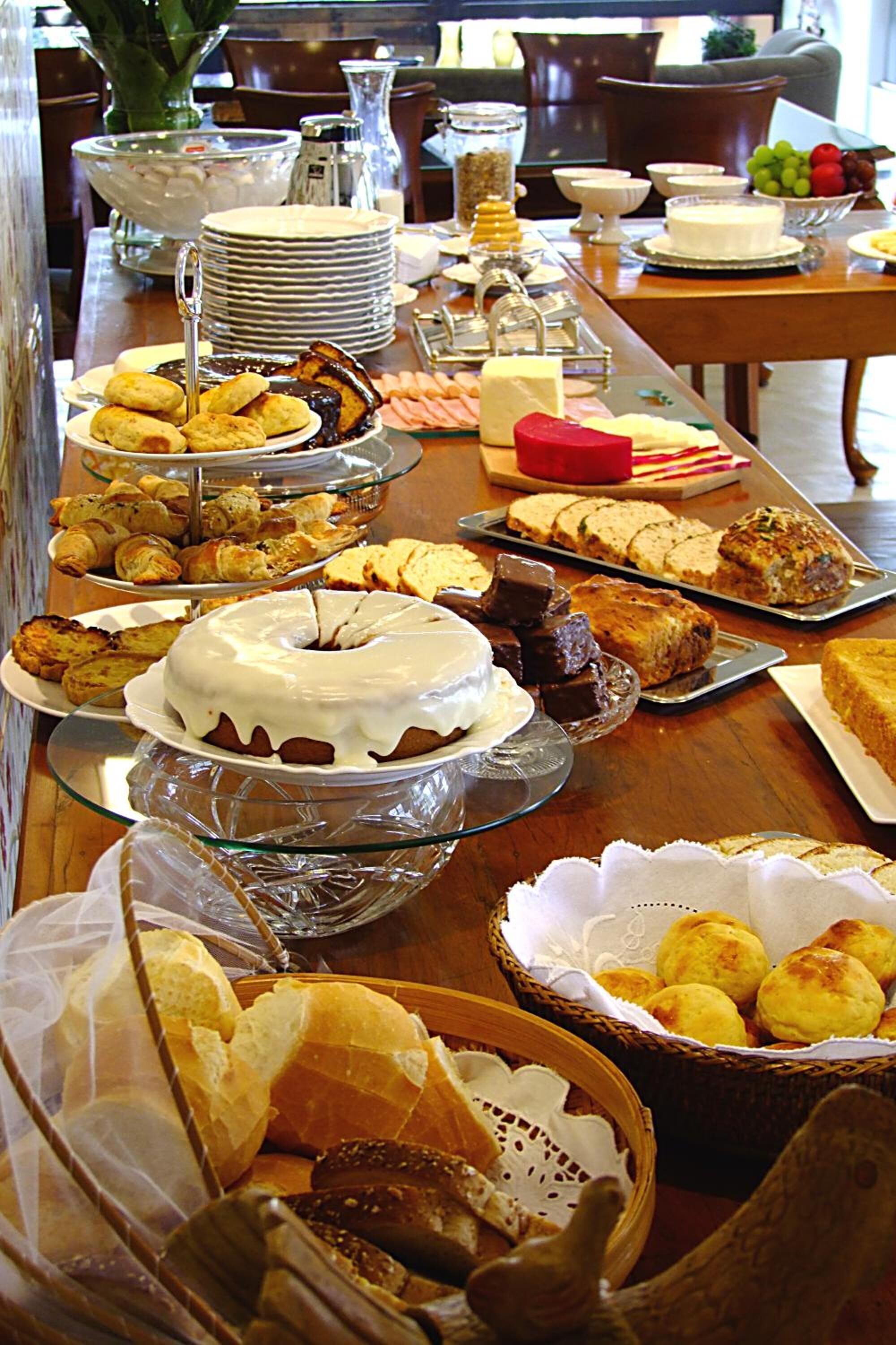 A buffet table with various food items, including cakes, pastries, and bread.