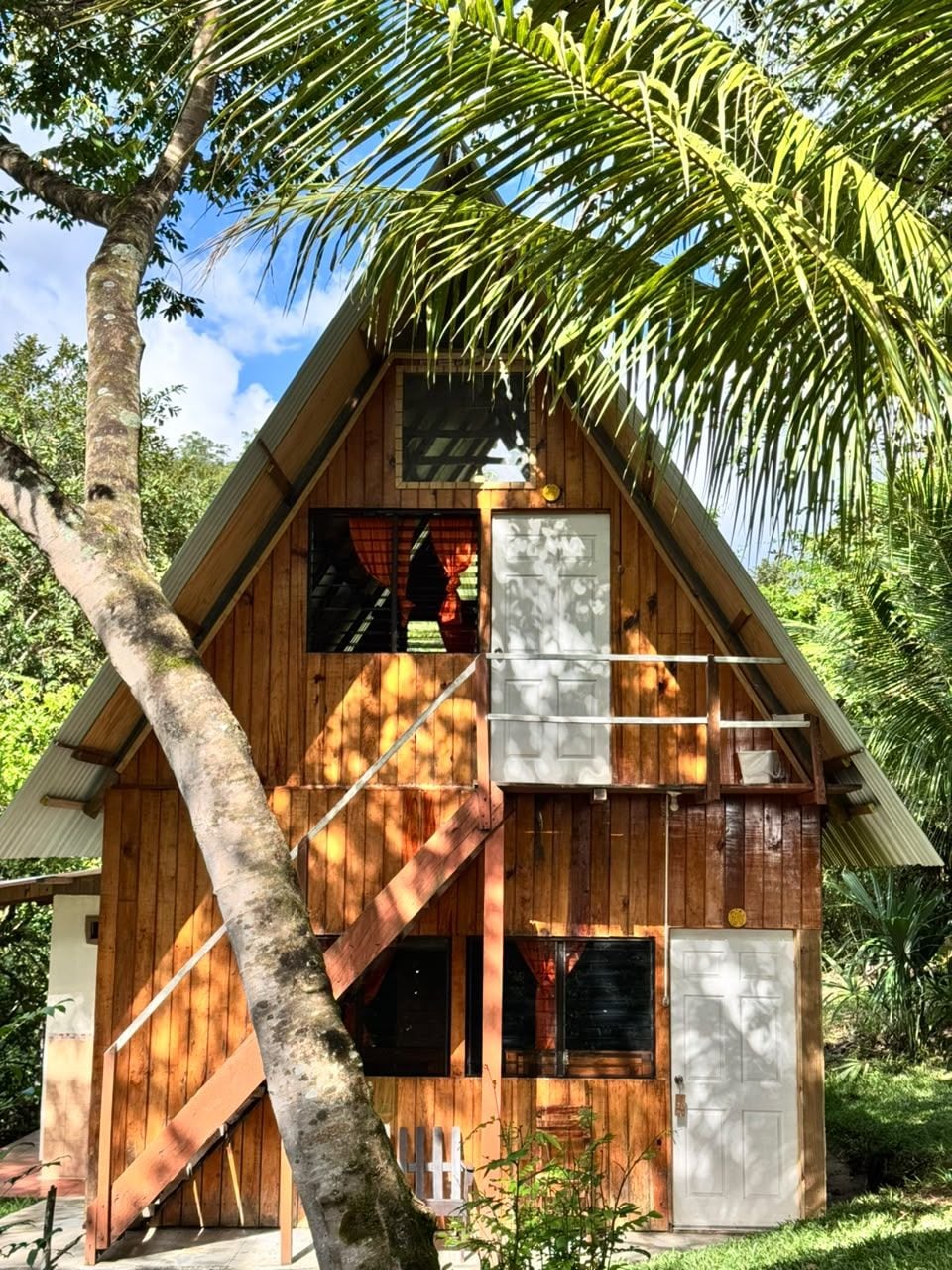 Eine Holzhütte mit einem steilen Satteldach, einer Veranda und einer Treppe zum Eingang.