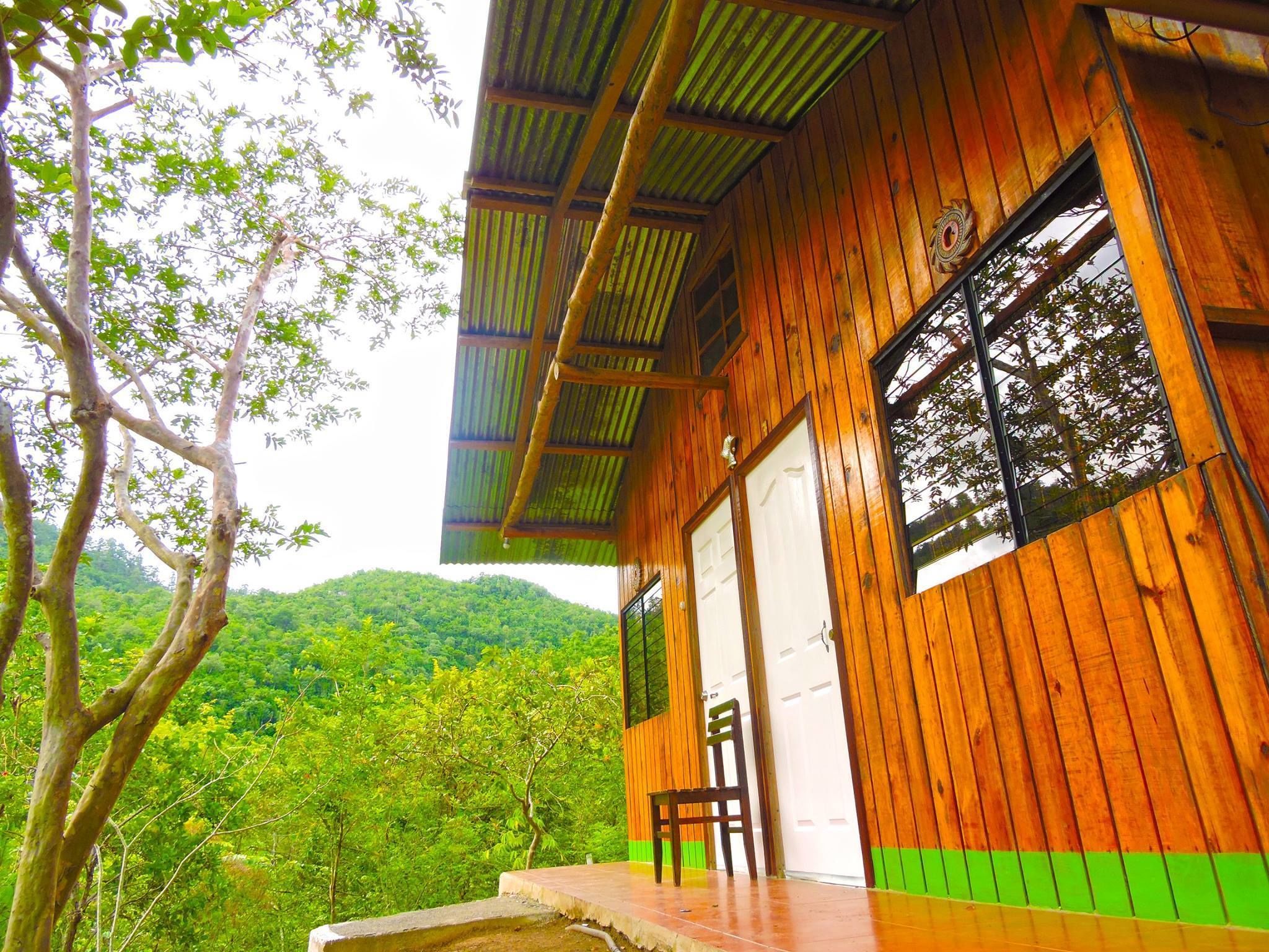 A wooden building with a porch, a chair, and a view of a green forest.