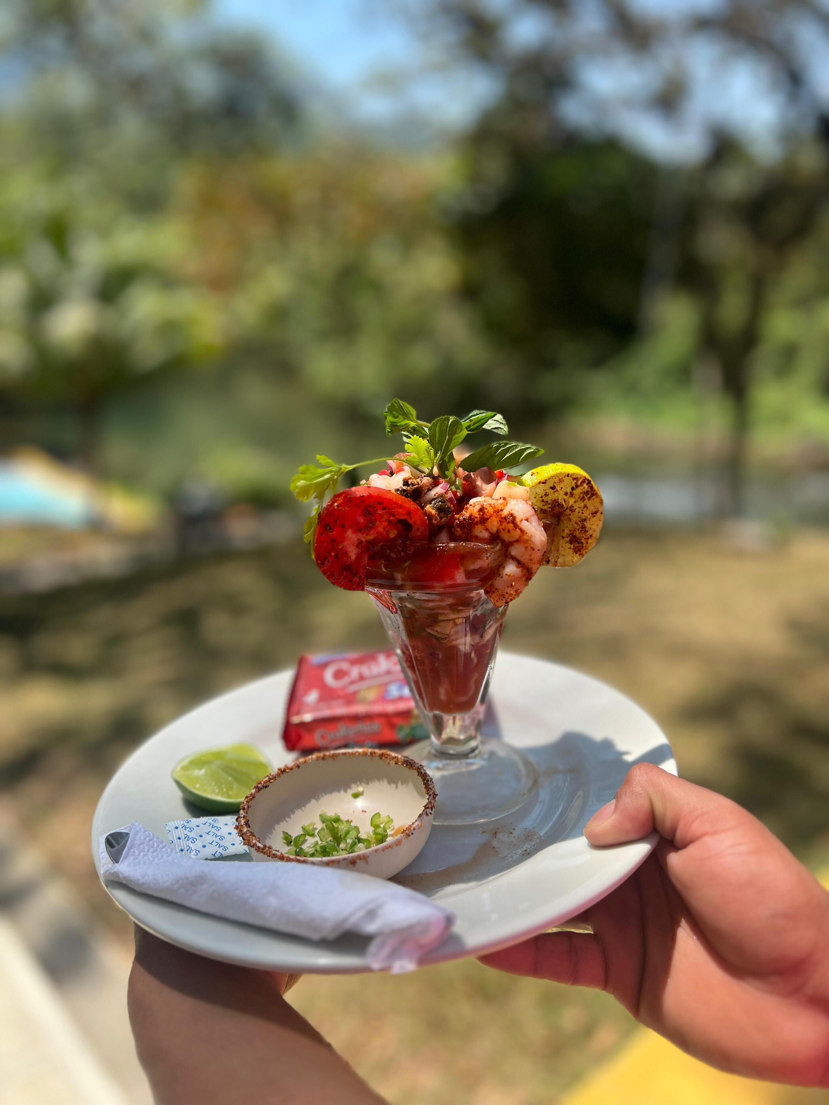 Ein Dessert mit Erdbeeren, einem Limettenschnitzel und einer kleinen Schale grüner Garnitur auf einem Teller.