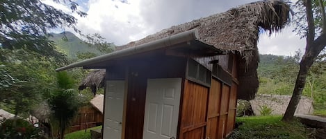 Una pequeña construcción de madera con techo de paja, una puerta y una ventana.