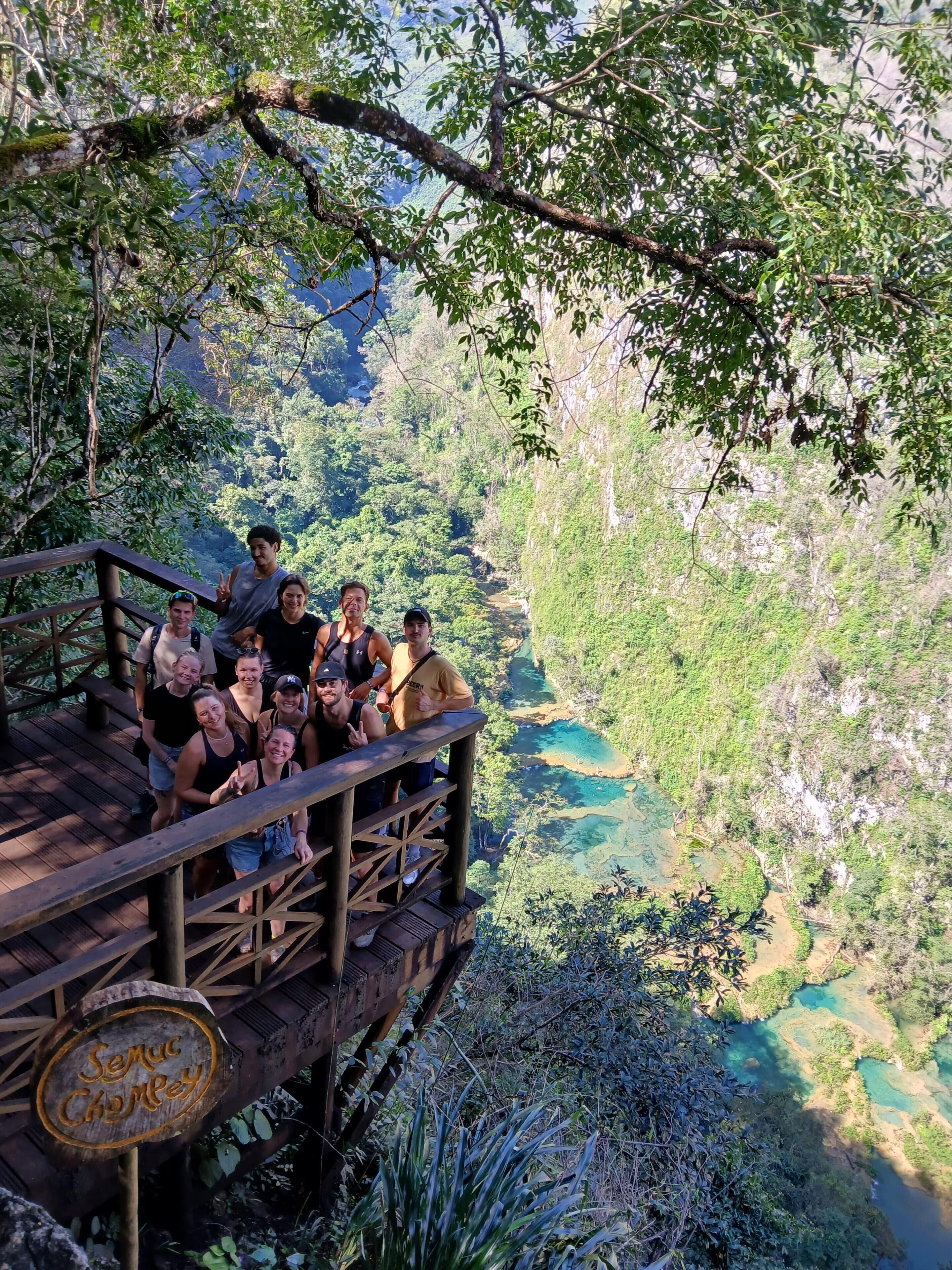 A group of people on a wooden bridge with a sign reading "Seru Charley".