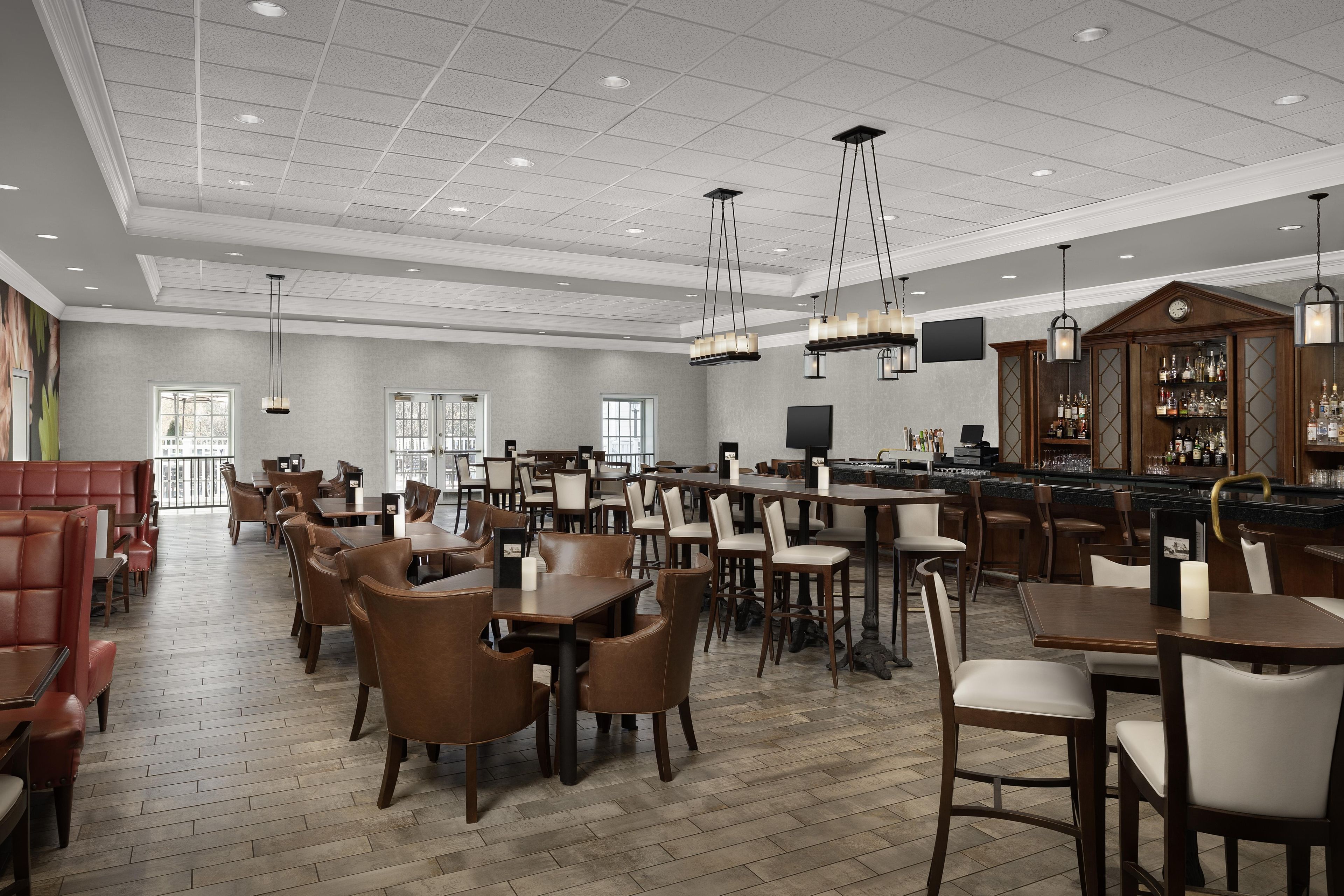 A spacious restaurant with multiple dining areas, a bar, and a bar area with a counter and stools.