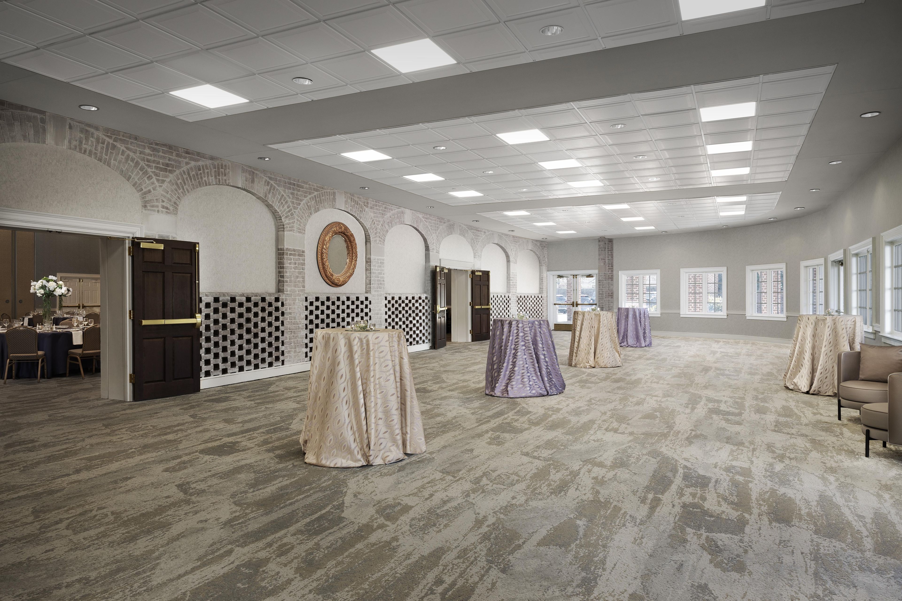Un hall d’hôtel spacieux, doté d’un plafond haut, de murs décorés de motifs et d’un sol recouvert de moquette.