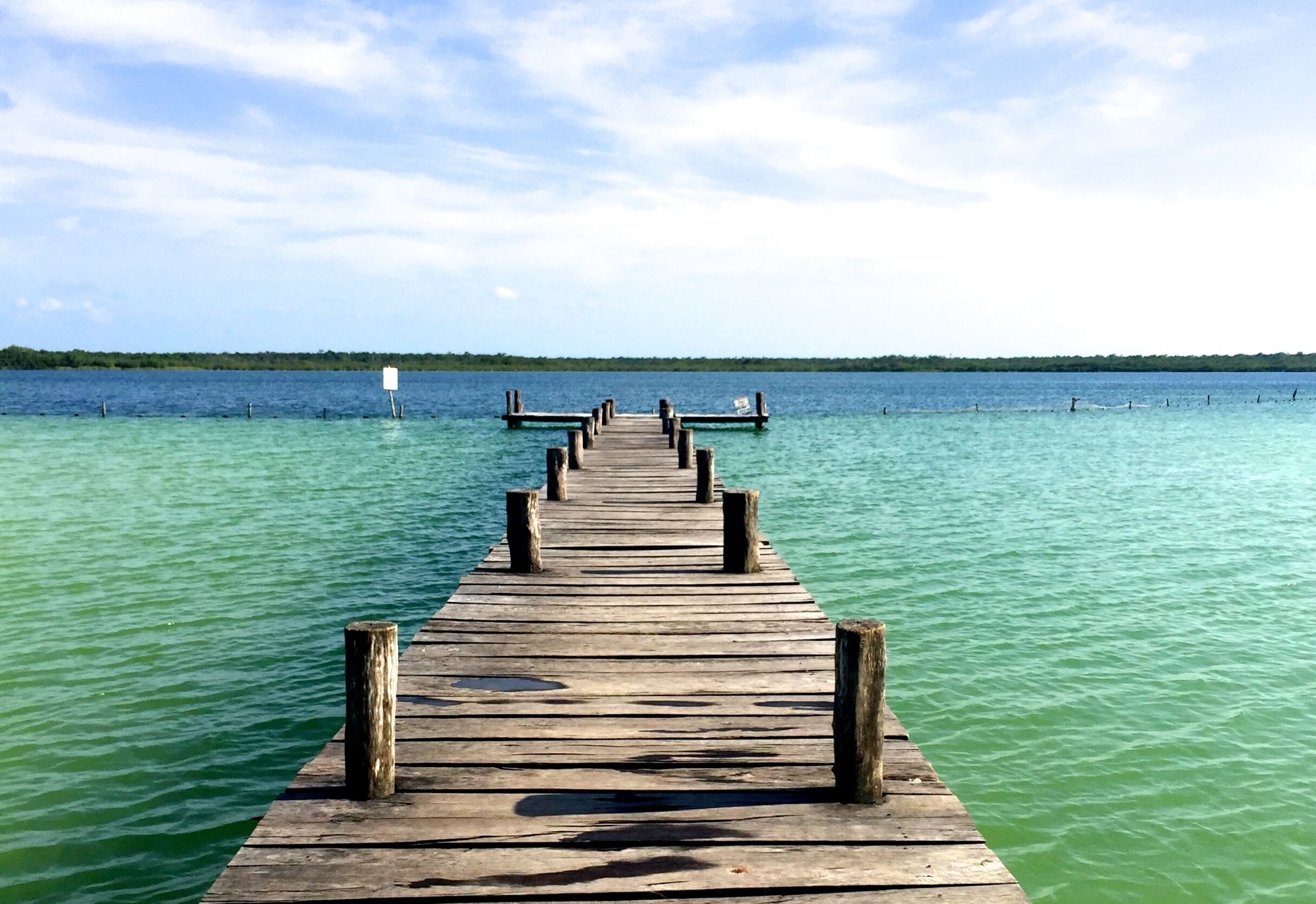 A wooden pier extending into a calm body of water with a clear sky above.