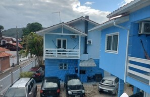 Un immeuble résidentiel à la façade bleue, doté d’un balcon et d’une terrasse carrelée.