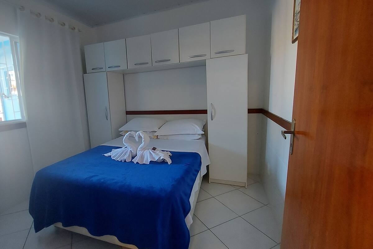 A bedroom with a bed, white cabinets, and a window.
