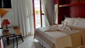 A hotel room with a bed, a desk, a lamp, and a view of the outside. - Pousada Estrela Guia (Florianópolis)