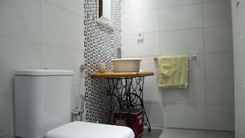 A small bathroom with a toilet, a sink on a vintage-style table, and a towel hanging on the wall.
